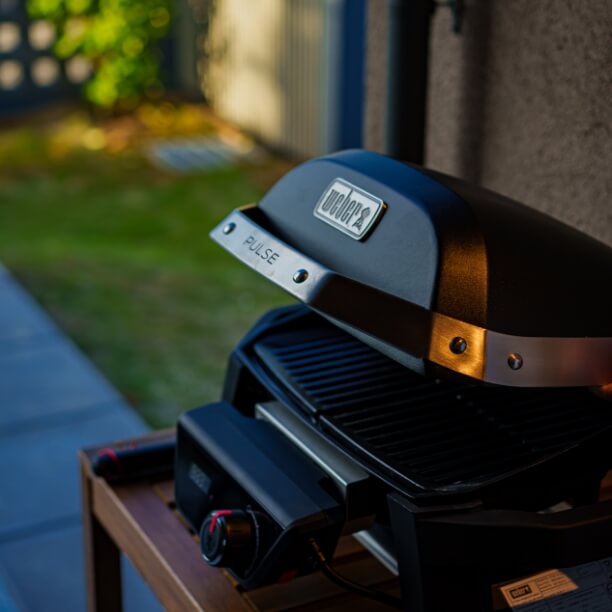 テラスに置かれたWeber製の蓋付きの黒いBBQグリル